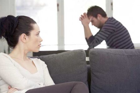 Woman looks at upset man sitting behind her