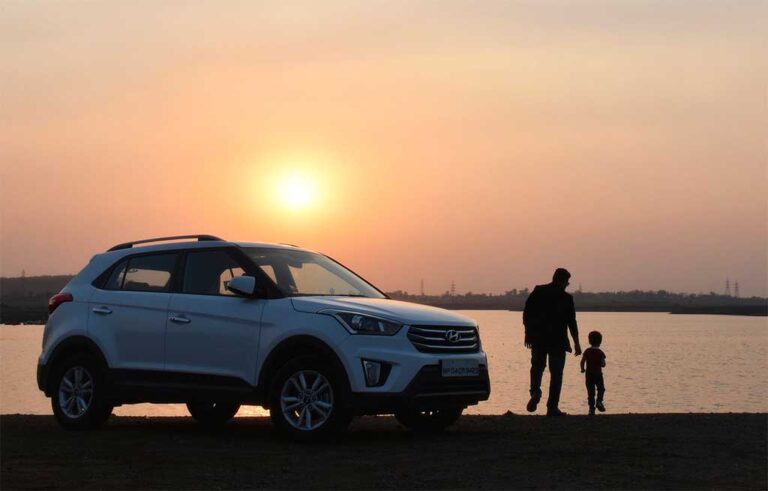 A man and a child standing next to a silver Hyundai Tucson SUV