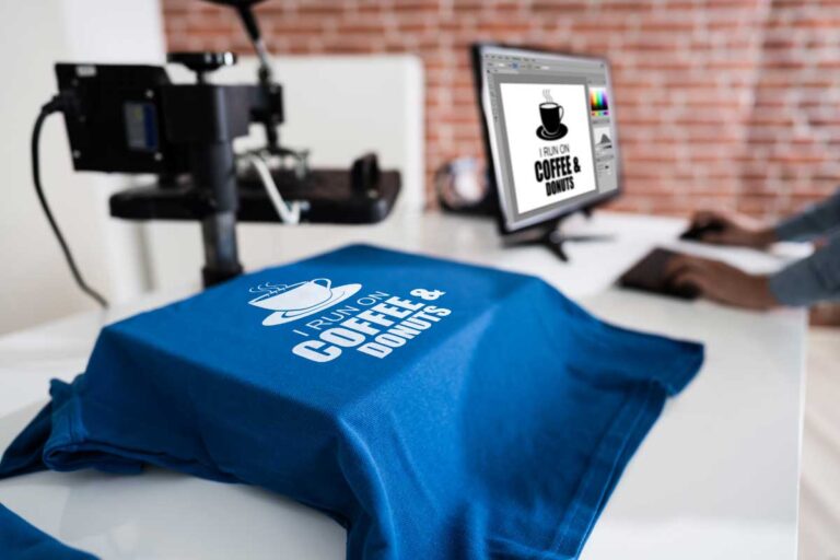 Blue custom-printed t-shirt with 'I run on coffee & donuts' design in a printing shop.