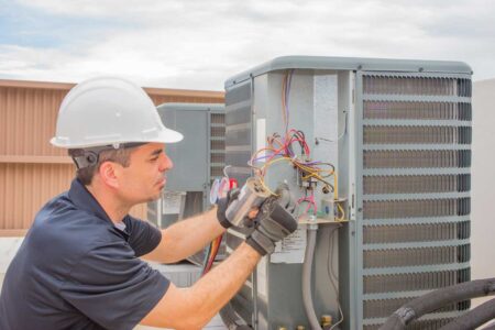 Technician repairing an HVAC unit with tools, focusing on maintenance work.