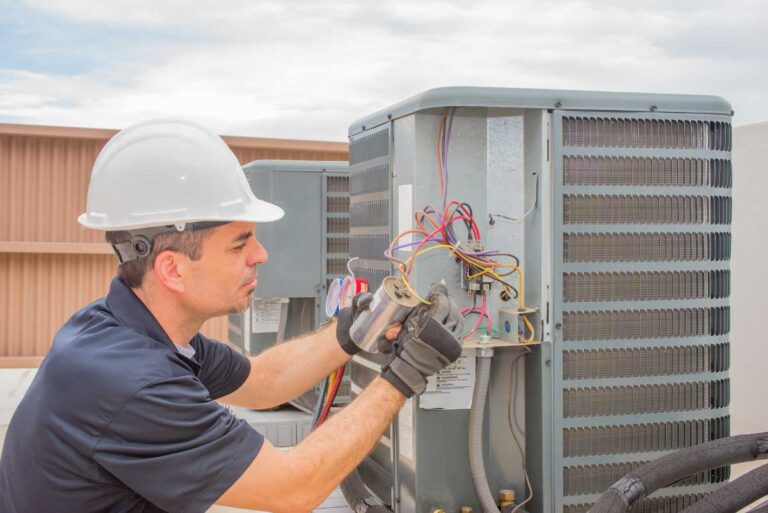 Technician repairing an HVAC unit with tools, focusing on maintenance work.