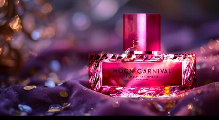 Vilhelm Parfumerie's Moon Carnival perfume bottle with radiant pink hue and gold accents on a purple backdrop.