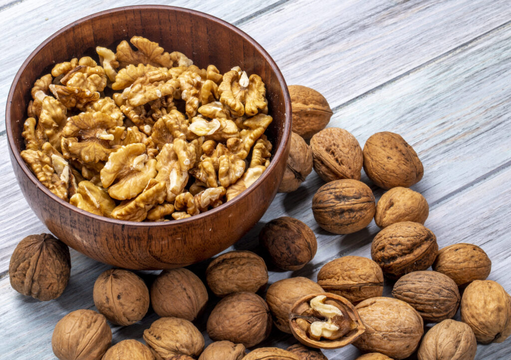 Side view of a bowl with walnuts on rustic background