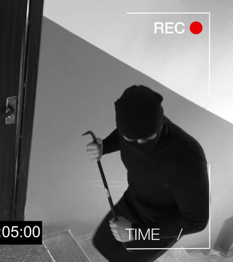 CCTV footage of a burglar walking upstairs with a crowbar. He’s wearing dark clothes with a black ski mask.