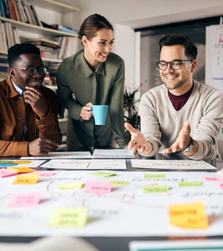 A group of marketing professionals smiling and looking at their marketing plans on the group desk.