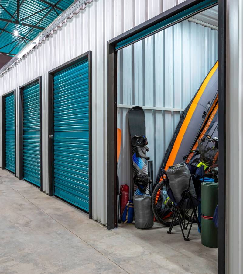 A look down a hallway in a self-storage facility. One of the storage units is open with the light on.