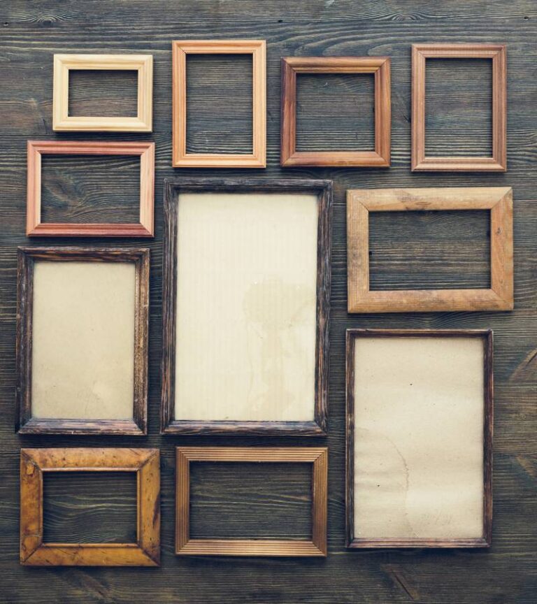 An assortment of empty, light brown wooden frames laying on top of a dark wood table. They range from small to large in size.