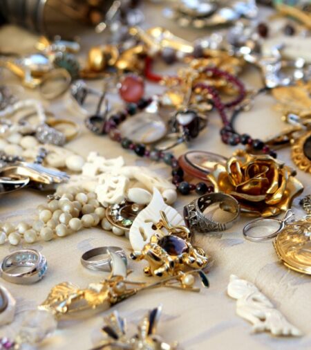 A table of antique jewelry. The pieces include necklaces, rings, broaches, and more. The background is slightly blurred.