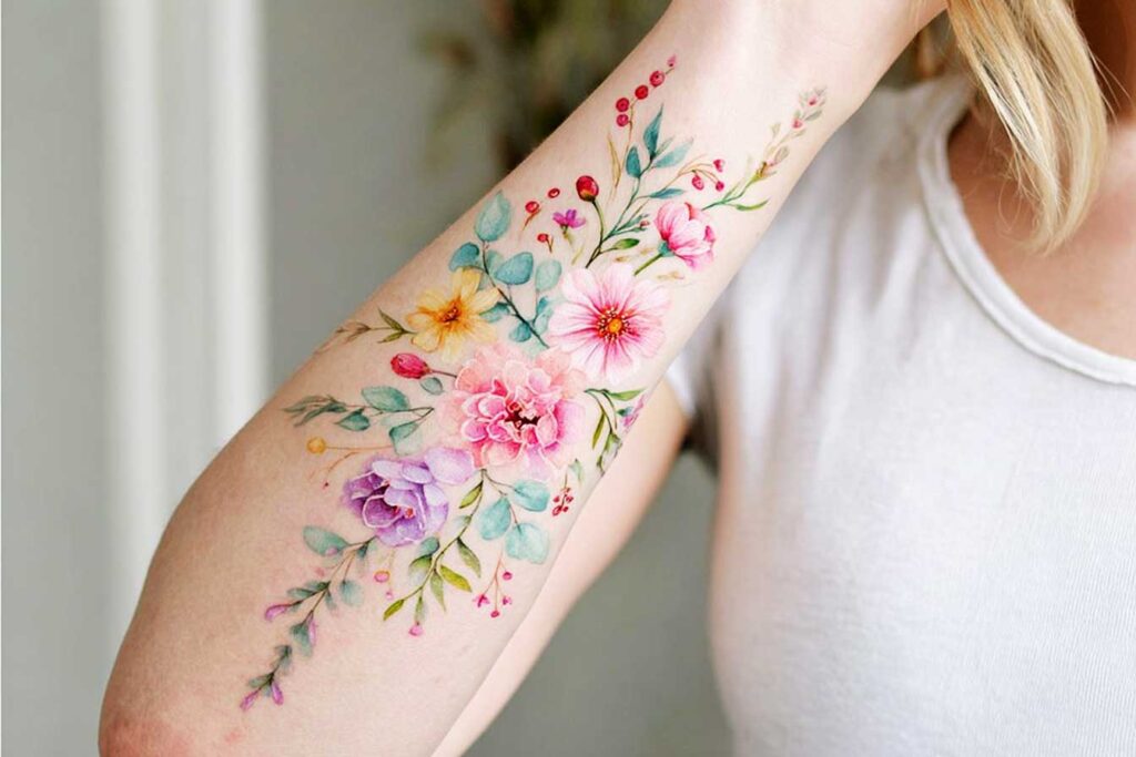 Pastel Tattoos, inner forearm of a woman, cascading bouquet of wildflowers and leaves