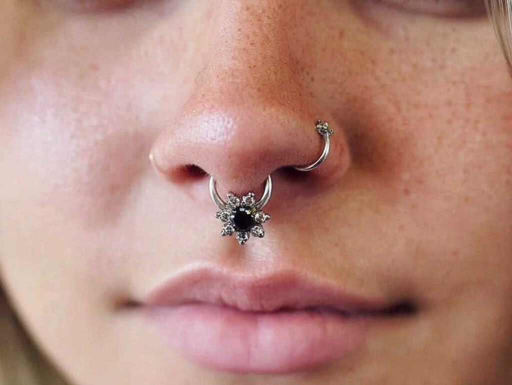 Closeup of freckled nose with silver floral septum ring and hoop