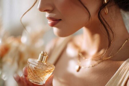 Close-up of a woman's neck and collarbone area as she gently sprays perfume